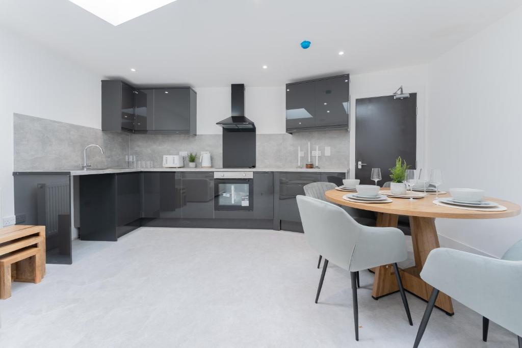 a kitchen with a wooden table and white chairs at 4 Bedroom modern apartment in Birkenhead