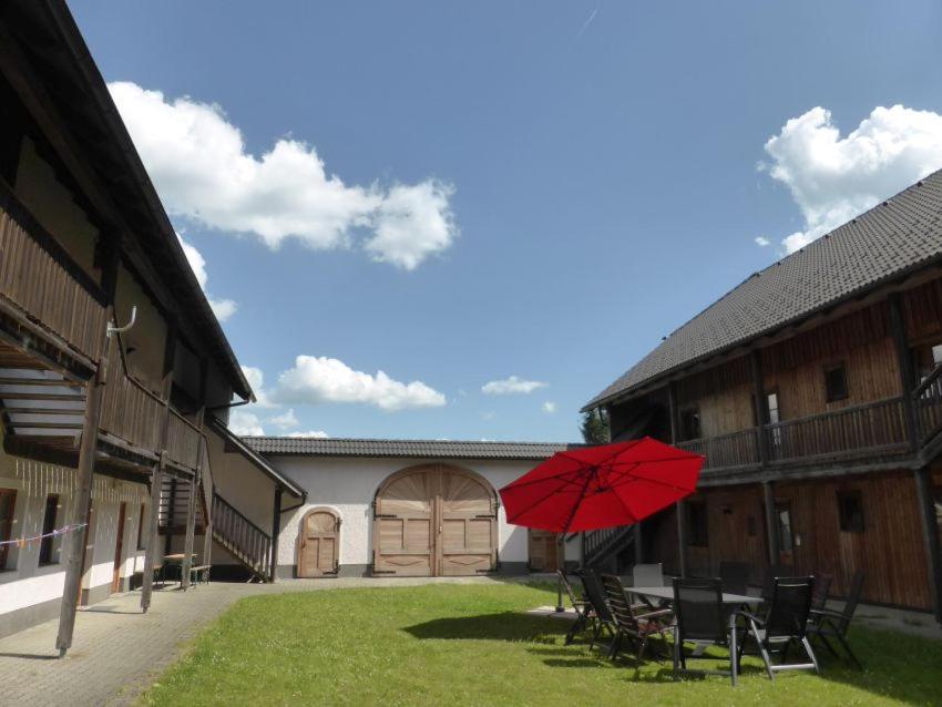 einem roten Regenschirm, der mitten im Innenhof sitzt in der Unterkunft Espi-Stables Ferienhof Esterhammer in Liebenau