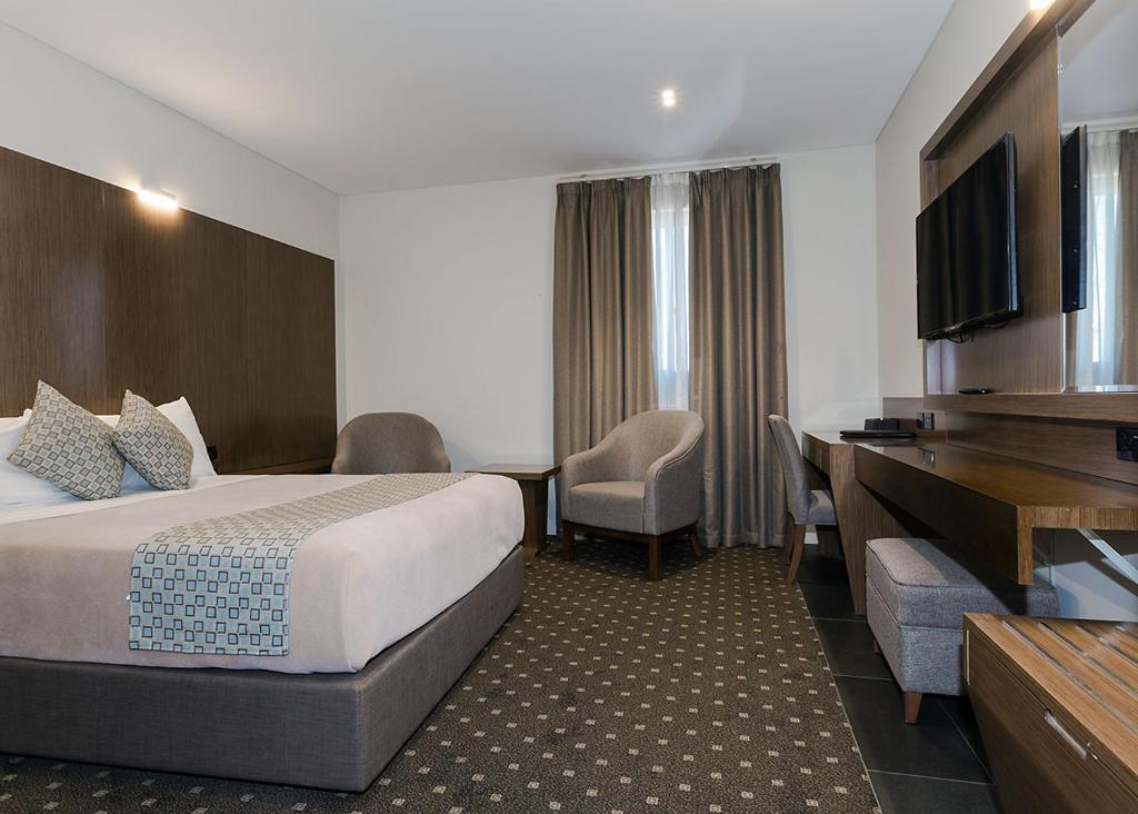 a hotel room with a bed and a flat screen tv at Bankstown Motel 10 in Bankstown