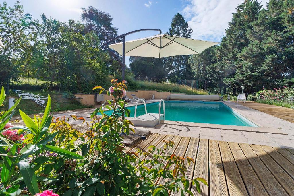 a swimming pool with an umbrella and a wooden deck at Maison Des Hôtes - Dordogne in Saint-Crépin-dʼAuberoche