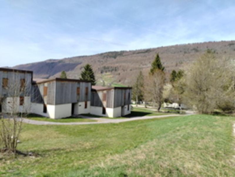 a row of houses in a field with a mountain at Résidence Vacancéole Les Monts Jura in Lélex