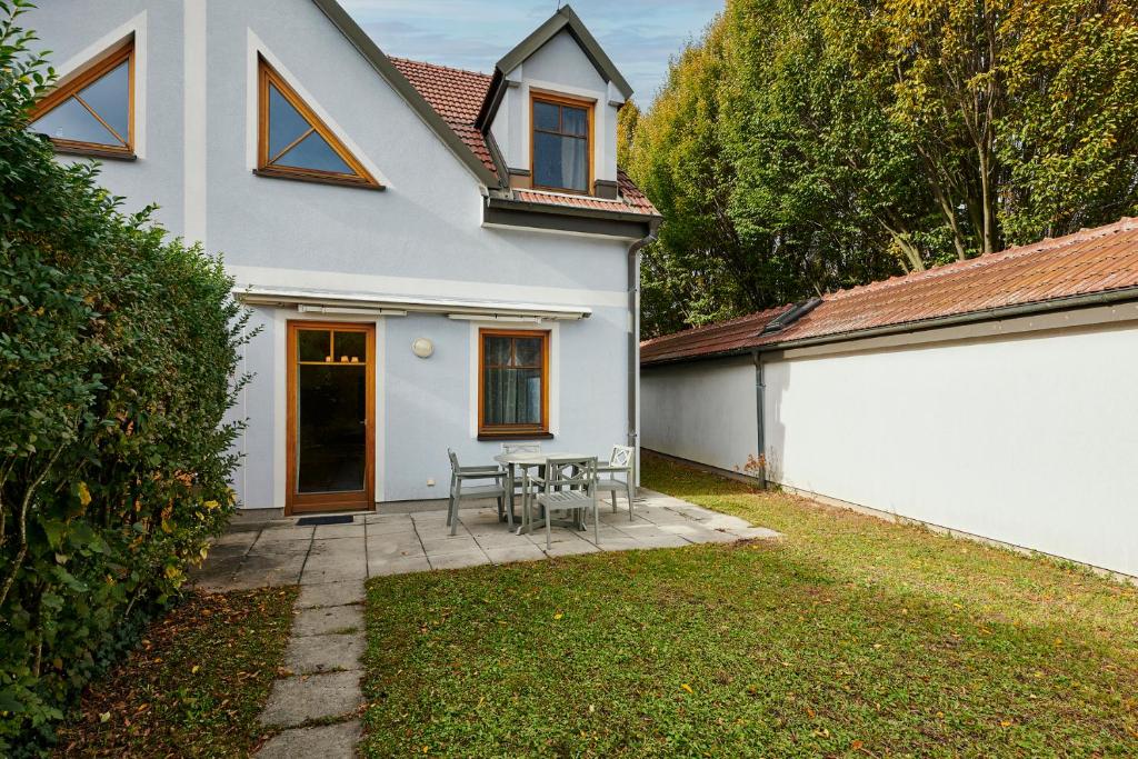 ein weißes Haus mit einer Terrasse mit Tisch und Stühlen in der Unterkunft DAS BURGENNEST Chalet 6 - Familienchalet für 5 mit privatem Bademantelgang zur Therme in Lutzmannsburg