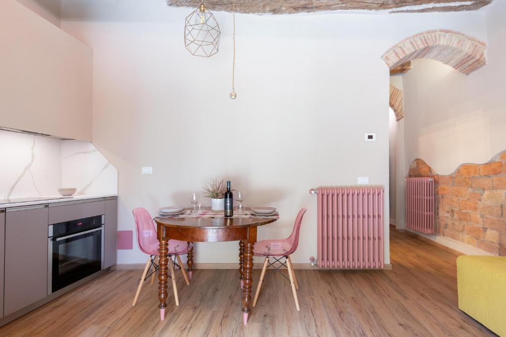 a kitchen with a wooden table and pink chairs at Il Poggiarello in Chianni