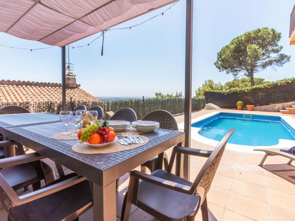 a table with a bowl of fruit on it next to a swimming pool at Holiday Home Panoramic by Interhome in Tordera