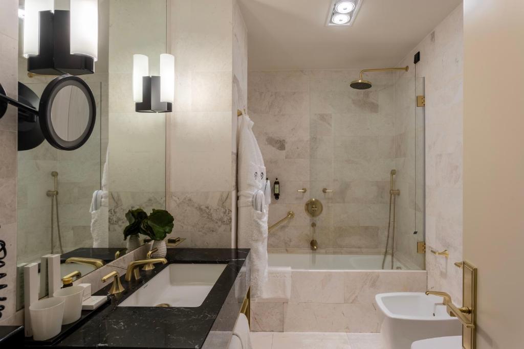 A marble bathroom with a black stone vanity, bathtub and bidet.