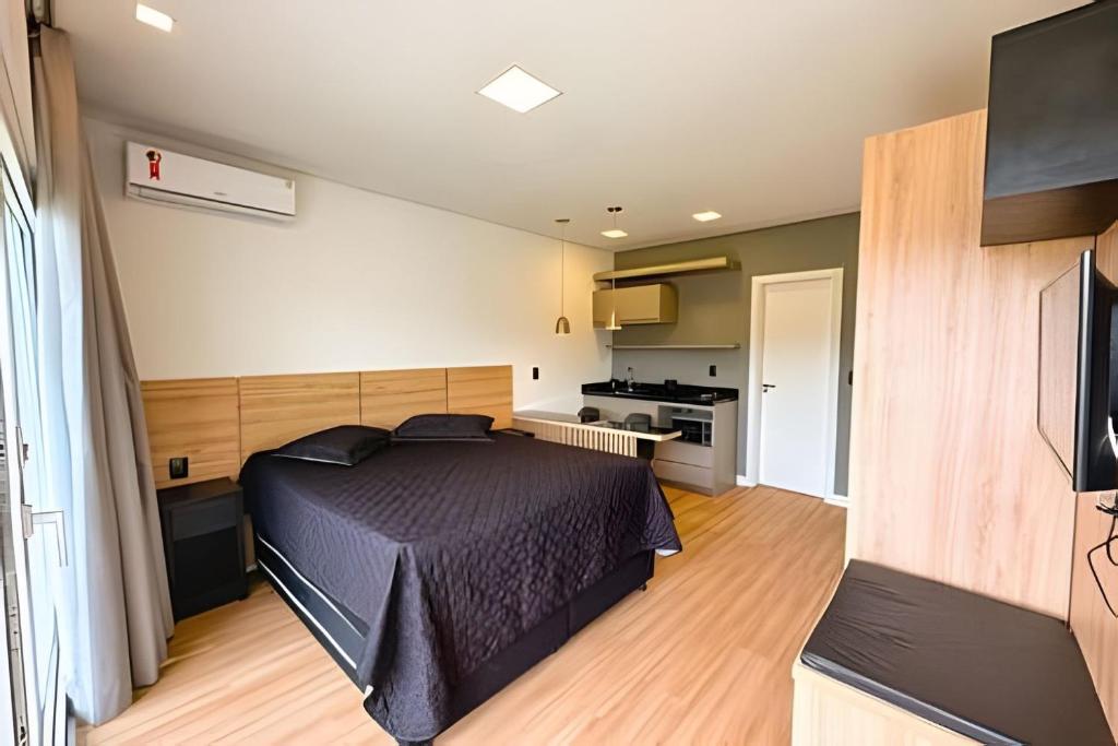 a bedroom with a bed and a kitchen at Condomínio Brises Downtown Garopaba in Garopaba