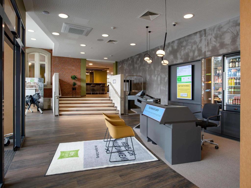 an office with a desk and chairs and a dog in the background at ibis Styles Coburg in Coburg