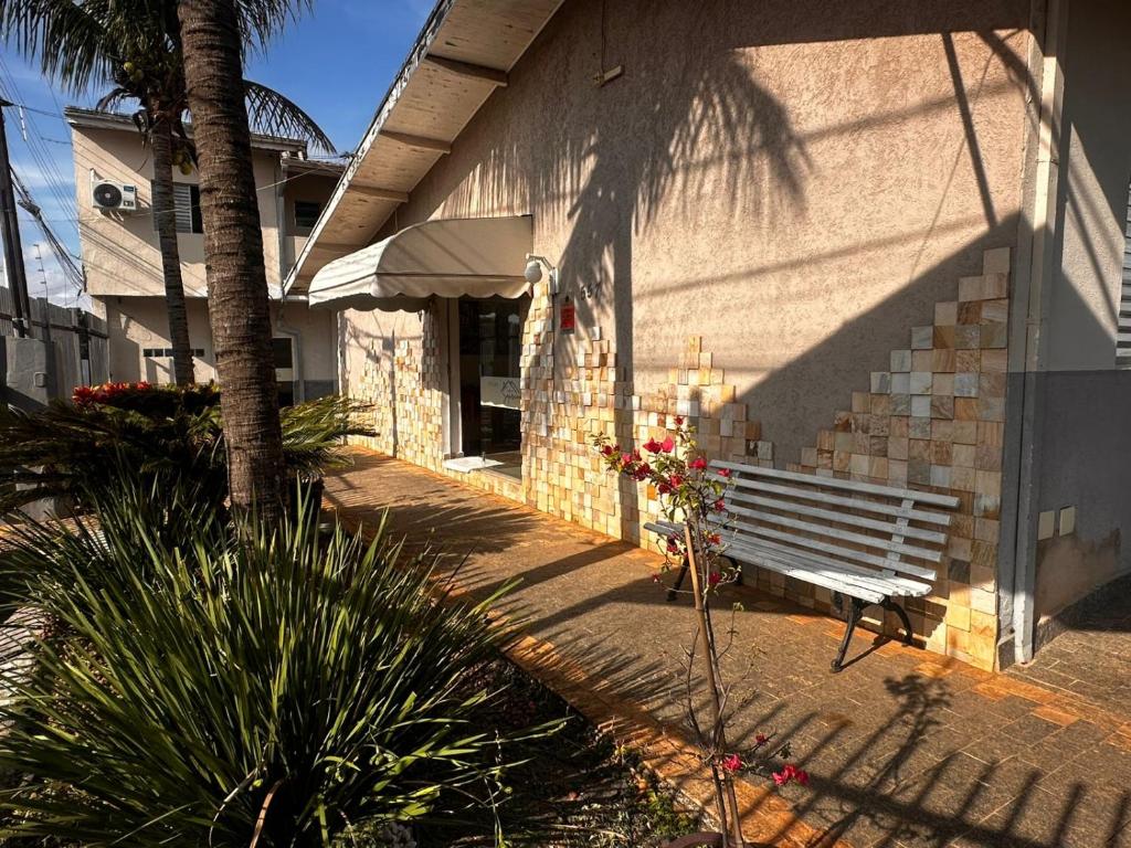 a bench sitting next to a building with a palm tree at Pousada Saturnino in Hortolândia