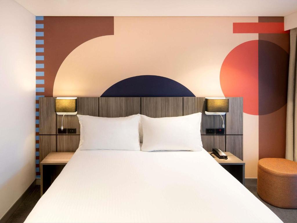 a bedroom with a large bed and a wall at ibis Styles Sydney Central in Sydney