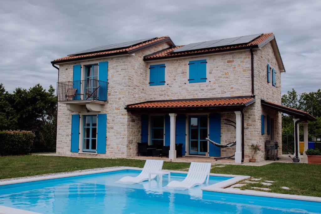 a house with a pool and two white chairs at Villa Francesca with Private Pool & Designer Interior in Kaštel