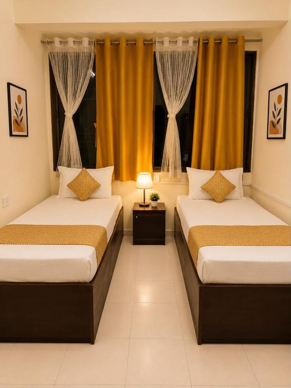 two beds in a room with yellow curtains at Elite Stays Viman Nagar in Pune