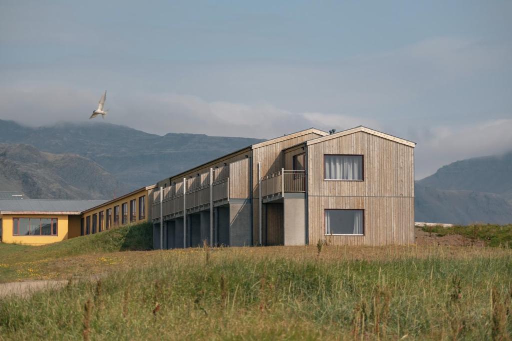 a building in a field with a helicopter in the sky at Hotel Langaholt in Langaholt