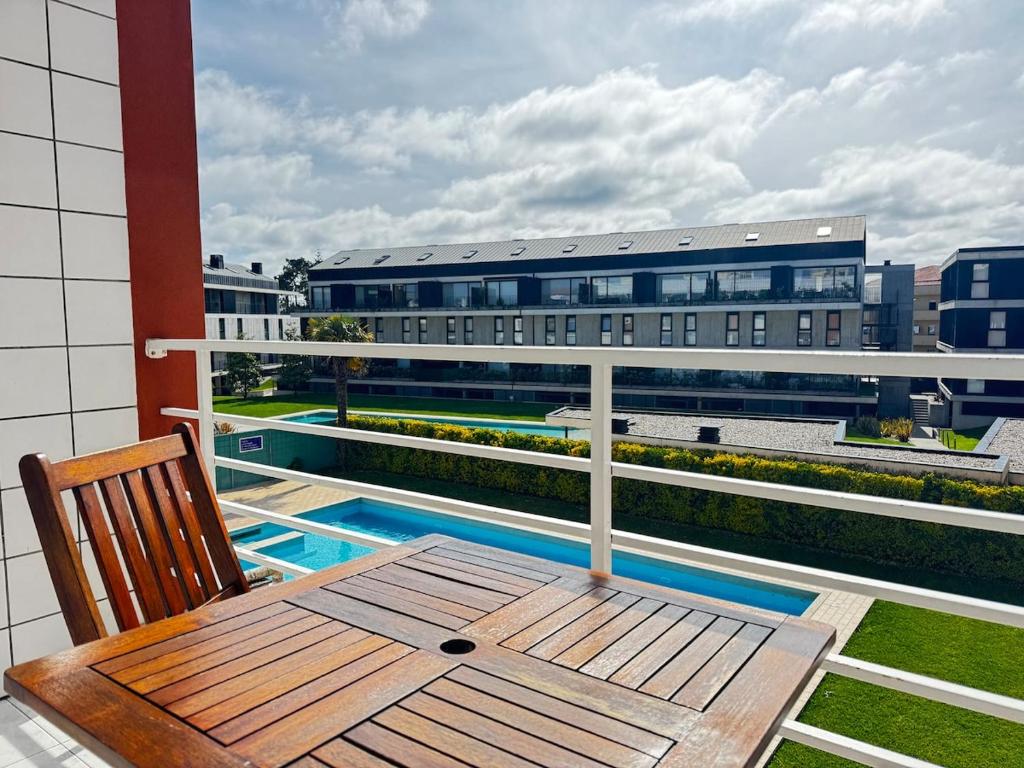 a balcony with a wooden table and a view of a building at Cavado Pool Apartment in Fão