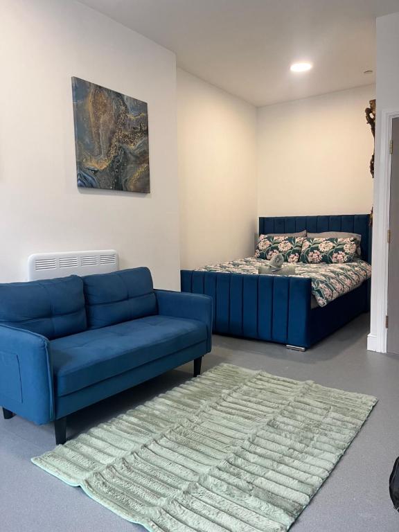 a living room with a blue couch and a bed at Cosy flat in central Cardiff Bay in Cardiff