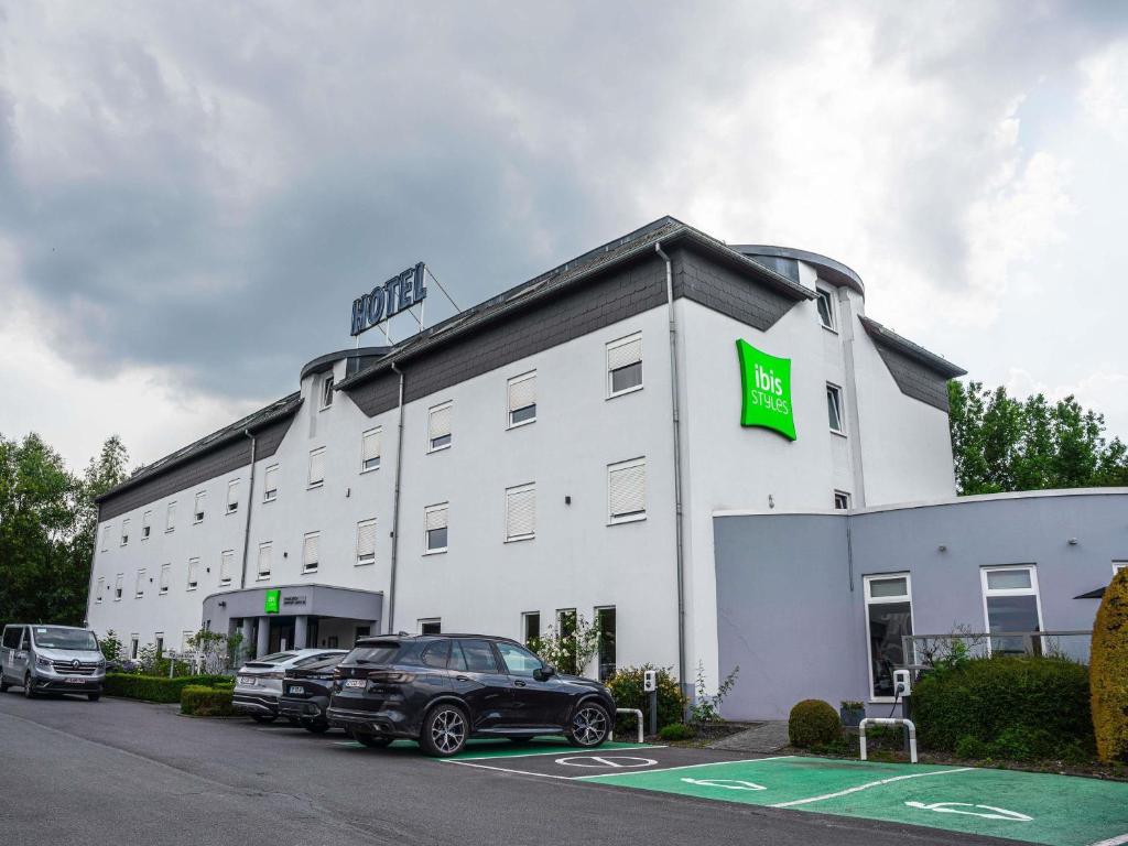a large white building with a green sign on it at Ibis Styles Charleroi Airport Aero 44 in Charleroi