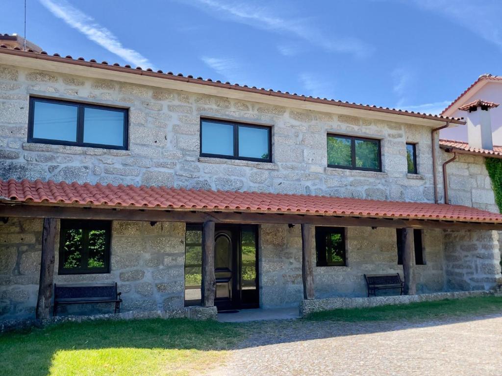 a large stone house with a red roof at Quinta do Eirô in Fonte Arcada