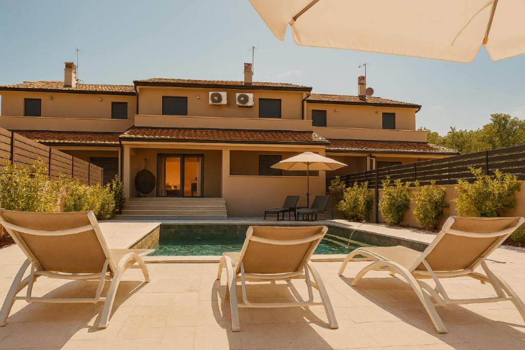 a house with two chairs and an umbrella and a pool at Casa ZOMABRIA in Poreč