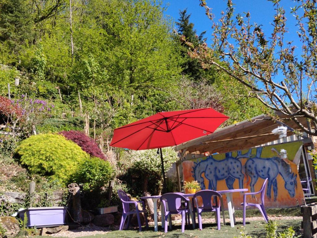 a red umbrella and some chairs and a table and chairs at Tiny House cosy, jardin romantique forestier, route du vin, sentiers in Lalaye