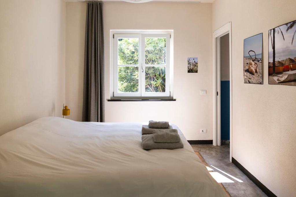 a bedroom with a large white bed with a window at Agriturismo Valleponci in Finale Ligure