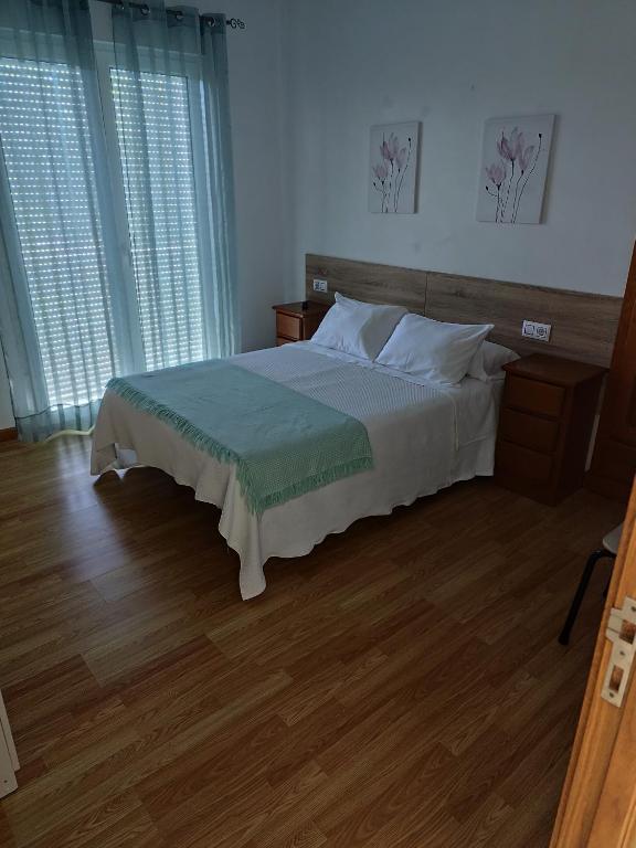 a bedroom with a large bed with wooden floors and windows at O marco da legua&camino de santiago in Piñor