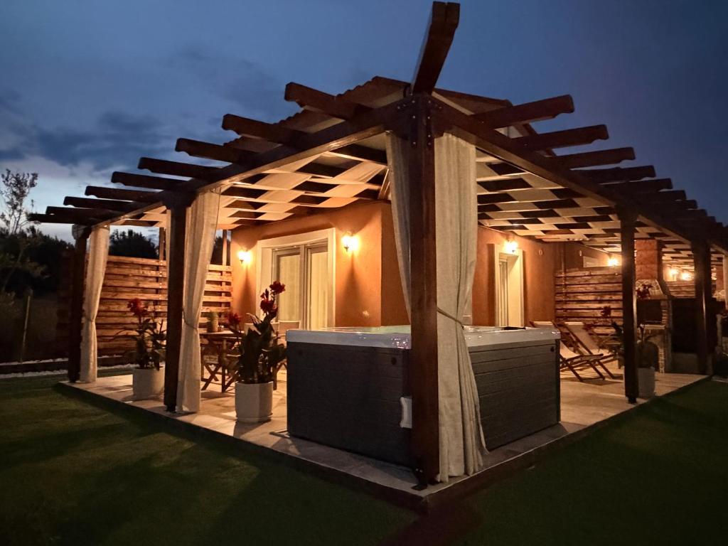 a wooden pergola with a tub in a yard at En Sophia Guesthouse in Maronia