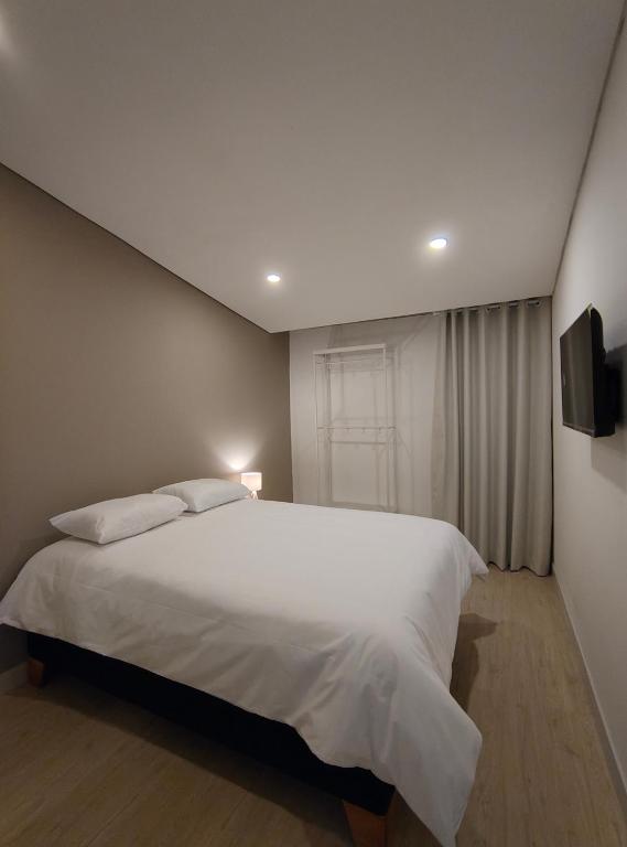 a bedroom with a large white bed and a television at Andes 97 Guest House in Bogotá