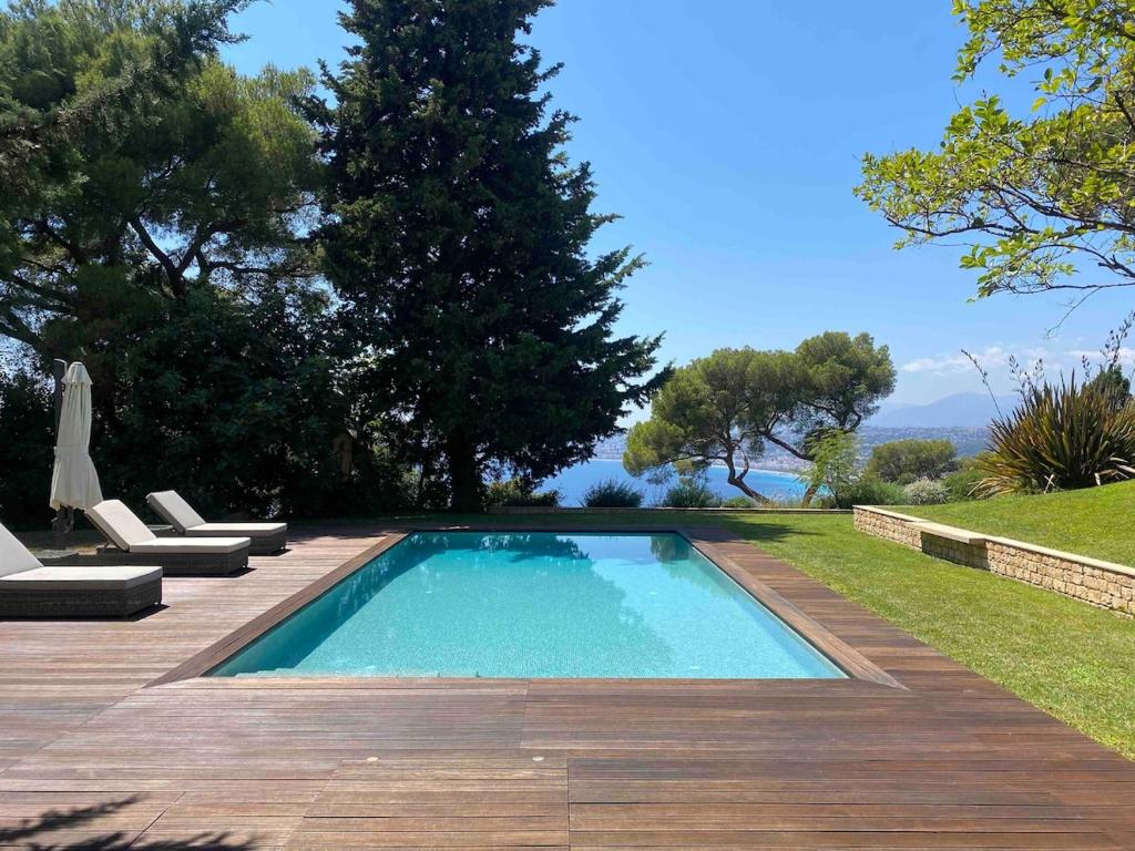 a swimming pool in a yard with a wooden deck at Villa Cœur de Mer in Nice
