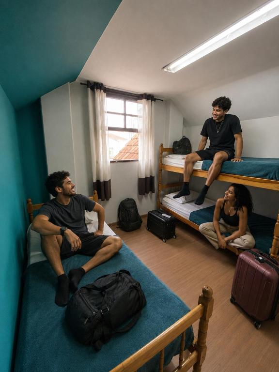 three people sitting on bunk beds in a room at Garibaldi Hostel & Pub in Curitiba