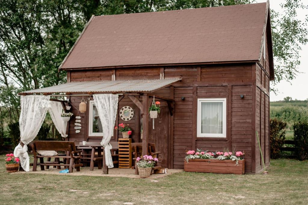 a wooden shed with a table and chairs and flowers at Nad Andruszkowianką in Andruszkowice