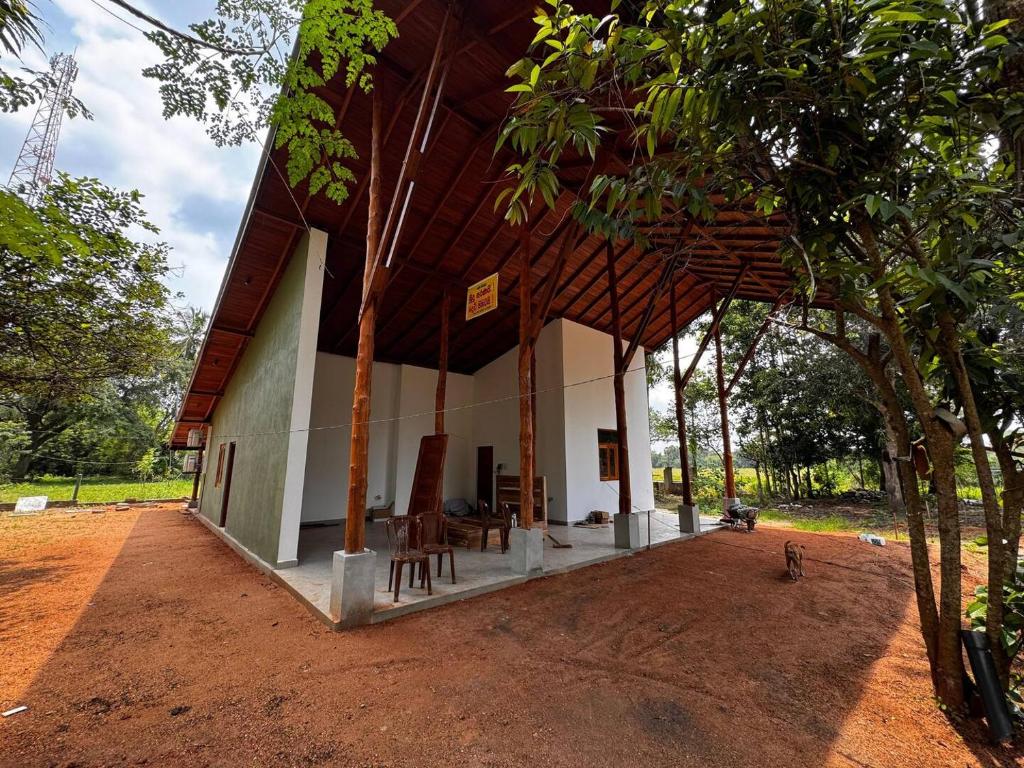 a house with a porch with chairs and trees at Safari Lodge Tempstay in Nochchiyagama