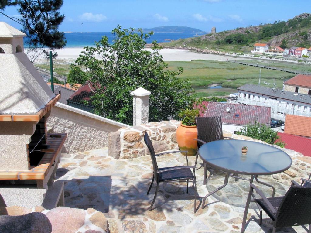 a patio with a table and chairs and the ocean at Apartamentos Playa Monte Pindo - Morada Druida in O Pindo
