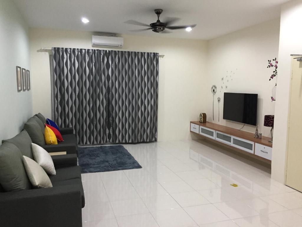 a living room with a couch and a television at Kt Cozy Lodge in Kuala Terengganu