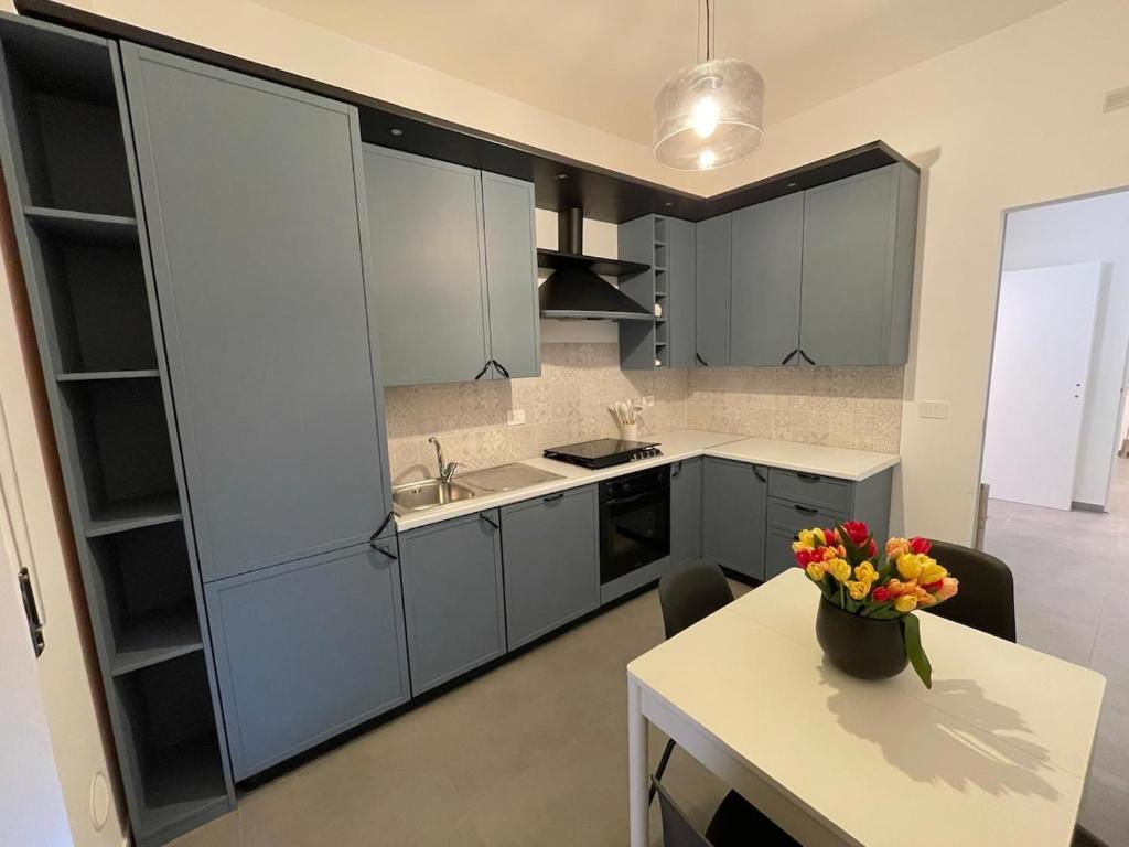 a kitchen with gray cabinets and a table with a vase of flowers at Moon Apartments B in Soverato Marina