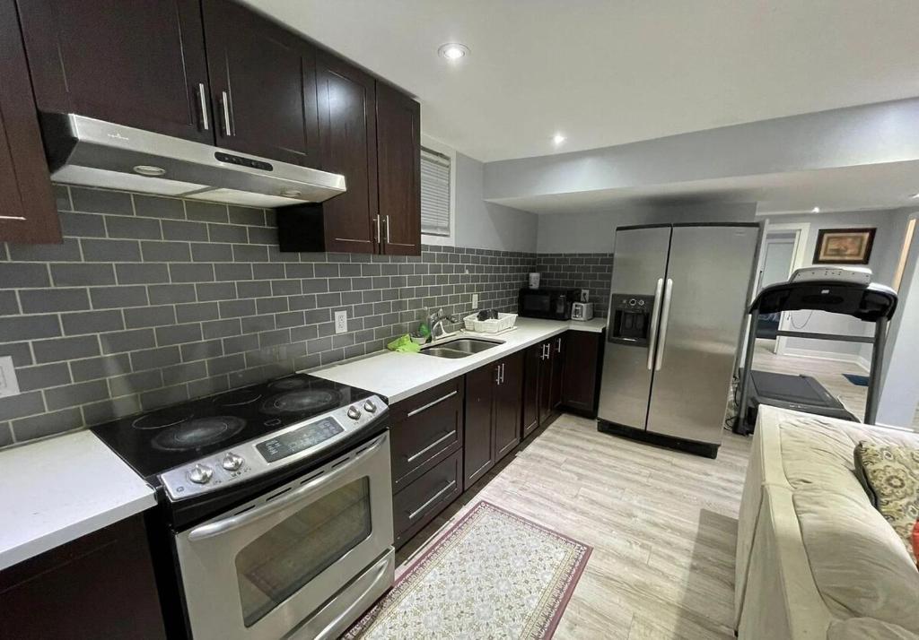 a kitchen with a stove and a refrigerator at Cozy & Spacious 2-Bedroom Basement Suite in Brampton