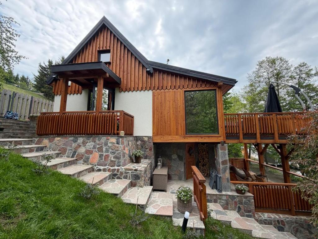 a house with a porch and a deck at Domek nad jeziorem z jacuzzi ROMANTICA in Wilamowo