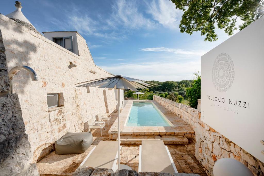 an external view of a building with a pool and an umbrella at TRULOCO NUZZI - LUXURY DOMUS in Locorotondo