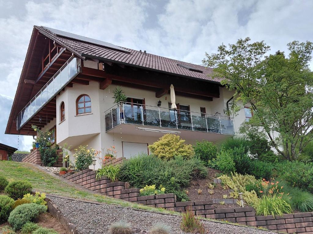 a white house with a balcony and some bushes at Ferienwohnung Himmelsbach in Schuttertal
