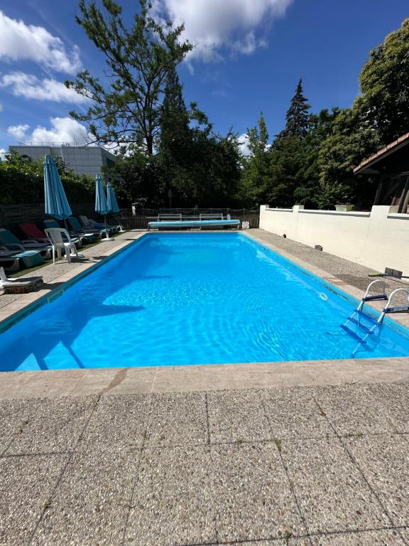 a large blue swimming pool with chairs and umbrellas at Aux Châtaigniers in Langon