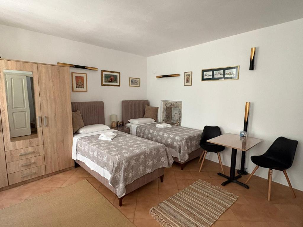 a room with two beds and a table and a desk at Old Town Mattarelli Studio in Kotor