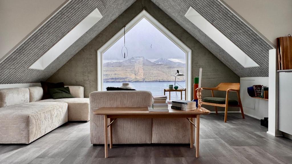 a living room with a table and a large window at Beitisstova - Mesmerizing Sea & Mountain Views in Stykkið