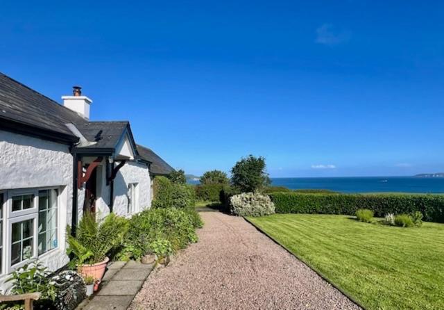 a house with a gravel driveway next to a yard at Tornaroan Cottage in Ballycastle