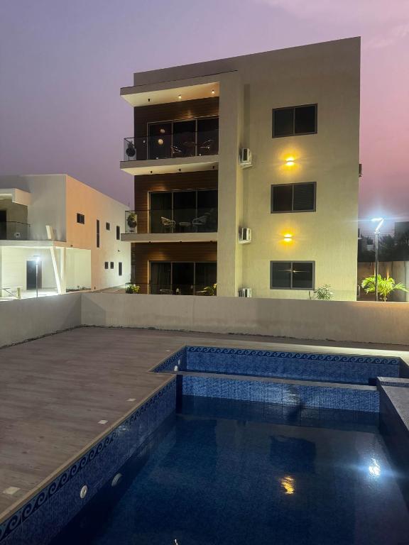 a swimming pool in front of a building at night at Horizon Apartment at THE HIDDEN DOMUS I Pool View in Accra