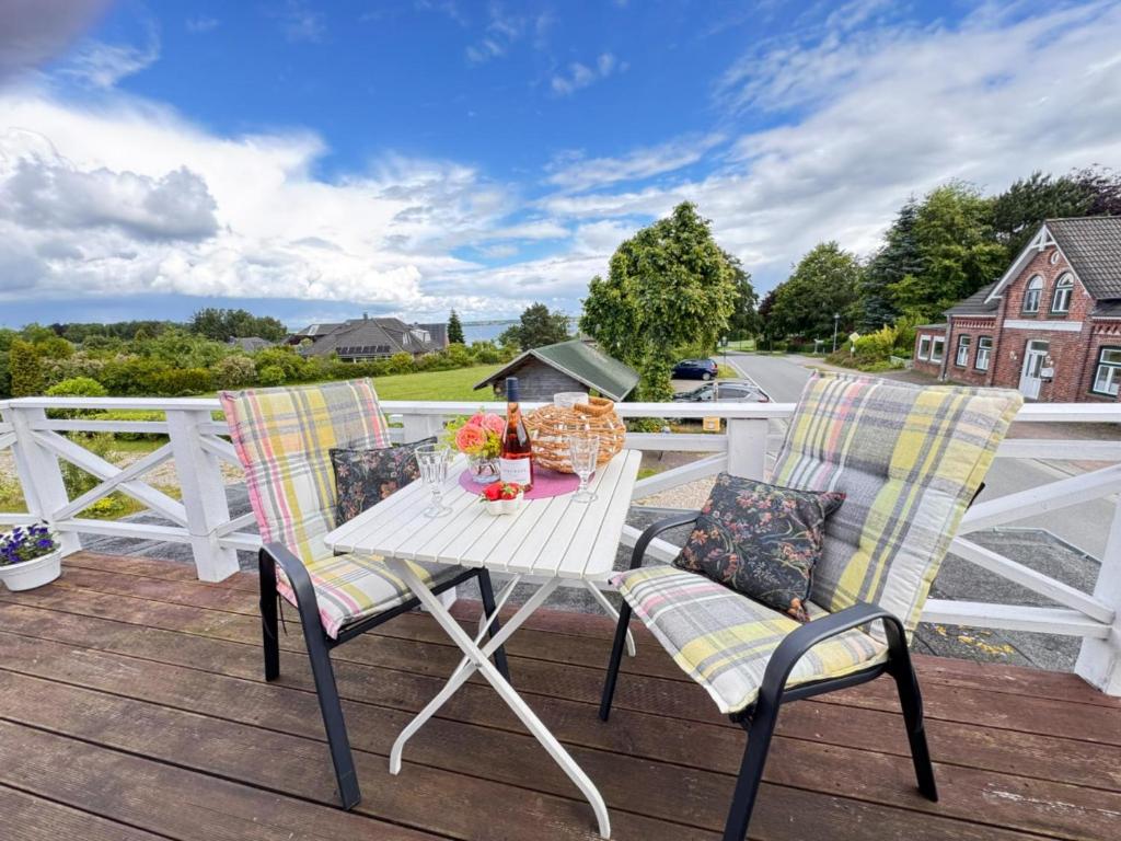 a table and chairs on a deck with a fence at Nordlicht, 1-Zimmer mit Meerblickbalkon 500 m zum Strand in Westerholz