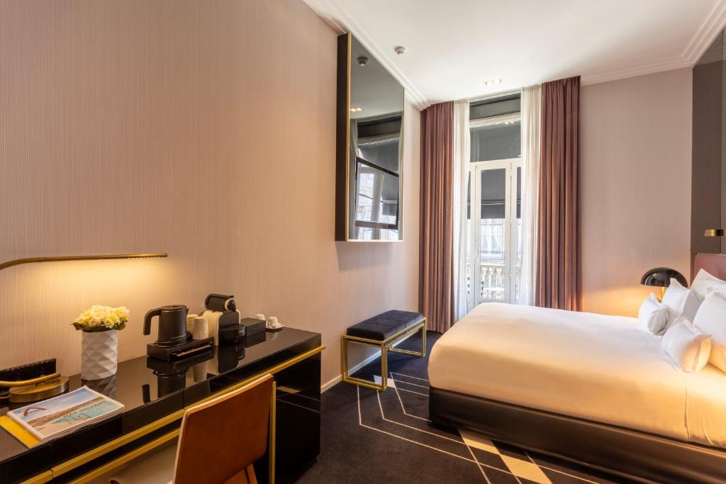 A compact in-room workspace beside a double bed, with coffee equipment and a city-facing window.