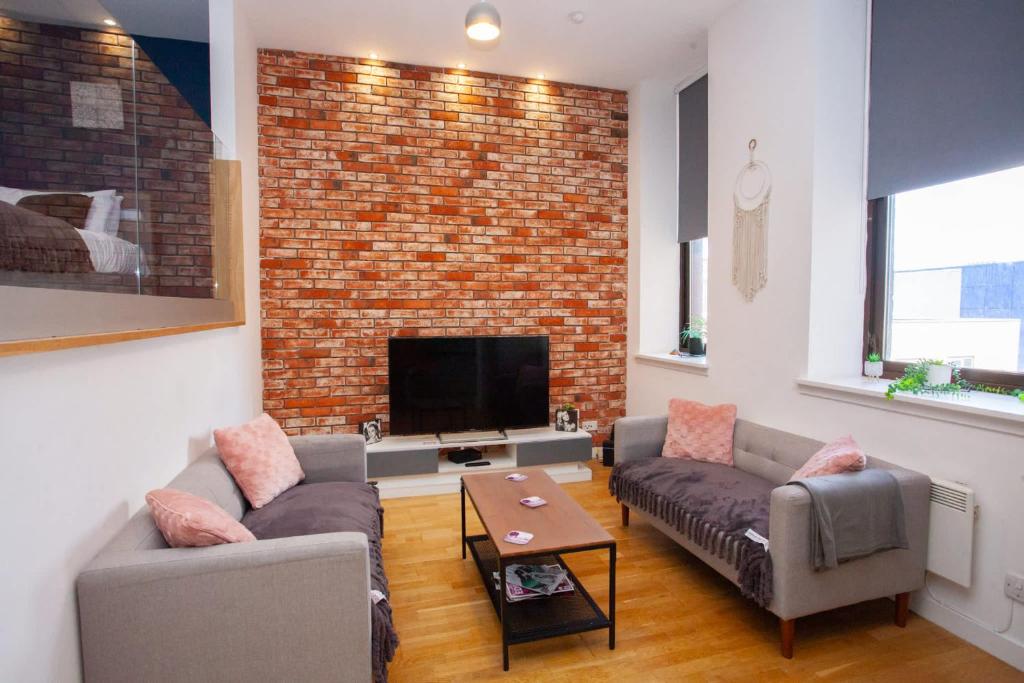 a living room with two couches and a brick wall at Stunning City Centre Duplex in Glasgow