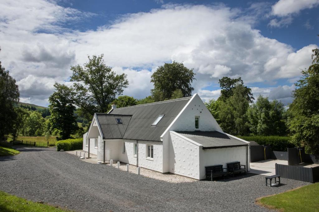 a white barn with a black roof on a gravel driveway at Big Lodge in Peebles