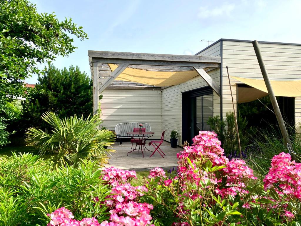 a house with a patio with pink flowers at Pavillon d'Éole in Berck-sur-Mer