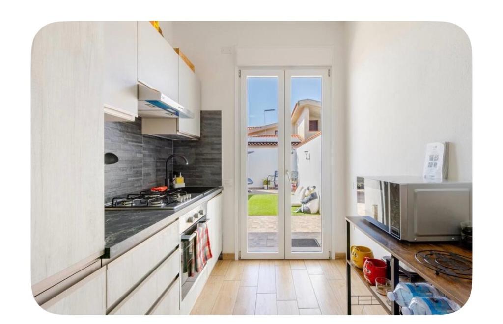 a kitchen with white cabinets and a door to a patio at Incanto patio house in Sestu