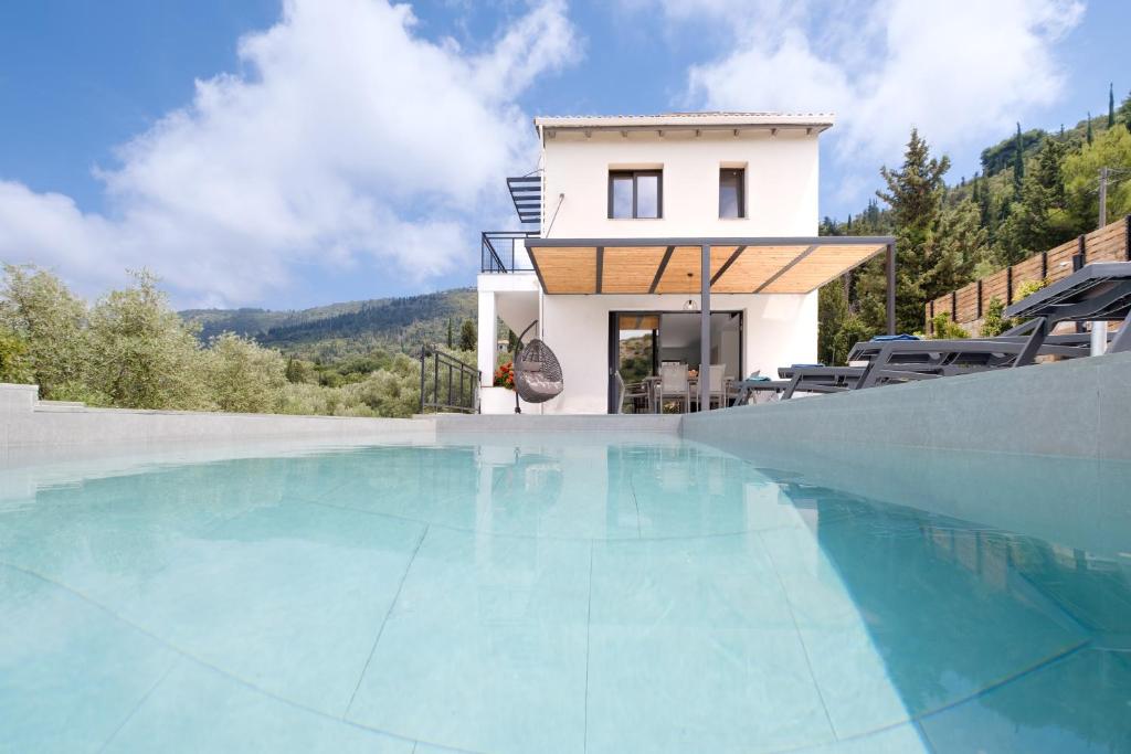 a villa with a swimming pool in front of a house at Villa Ilianthi in Kalamitsi