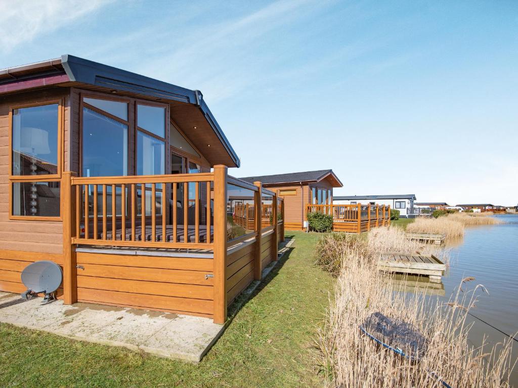 a house on the shore of a lake with a deck at Buff Lake - Uk37725 in Ingoldmells
